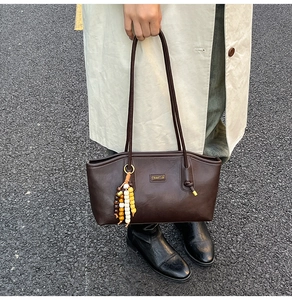Detail of vintage coffee brown tote bag featuring colorful bead charms and metal logo