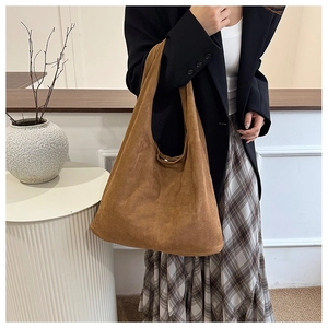 Detail view of brown suede hobo tote bag with wide shoulder strap and magnetic closure