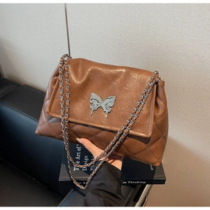 Détail du sac matelassé caramel avec boucle papillon argentée et bandoulière en chaîne
