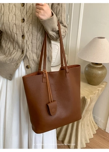 Close-up of dark brown tote bag with leather texture and matching small pendant charm