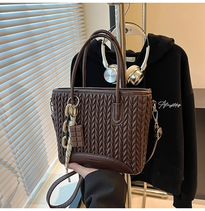 Detail of dark brown tote bag featuring V-shaped quilted texture and chocolate pendant