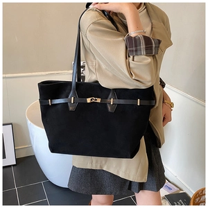 Detail of black suede tote bag with golden metal twist lock and decorative leather strap