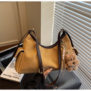 Dettaglio borsa hobo in camoscio zenzero con tracolla in pelle e ciondolo a forma di cane