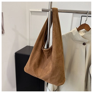 Close-up of brown suede hobo bag with soft texture hanging on a metal stand