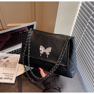 Détail du sac cabas en cuir noir avec boucle papillon argentée et bandoulière