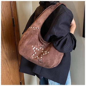 Detail of vintage brown suede shoulder bag with silver rivet star pattern on model
