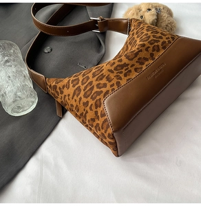 Detailed view of leopard print texture and embossed logo on brown crossbody bag