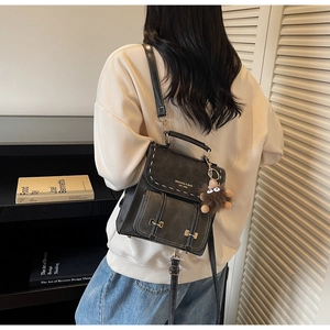 Dettaglio dello zaino vintage in PU nero con cuciture a contrasto bianche e peluche