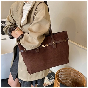 Close-up of a brown suede tote bag with leather strap detail on a stylish model