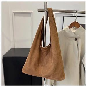 Close-up of brown suede hobo tote bag featuring a minimalist seamless shoulder strap design
