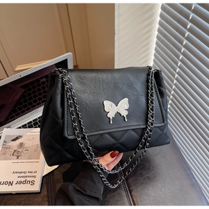 Détail du sac à bandoulière noir matelassé avec fermoir papillon argenté et chaîne