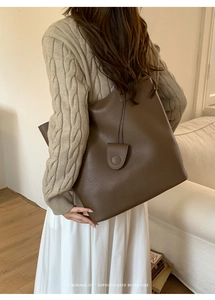 Close-up of a dark brown litchi pattern tote bag styled in a minimalist room