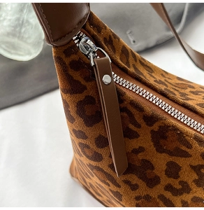 Detailed close-up of the smooth leopard print faux suede fabric and silver metal zipper