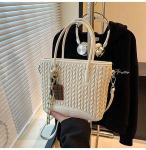 Detail of off-white quilted bucket bag with V-weave texture and chocolate charm