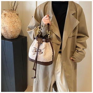 Detail of plush bucket bag with cream faux fur, brown leather accents, and gold chain strap