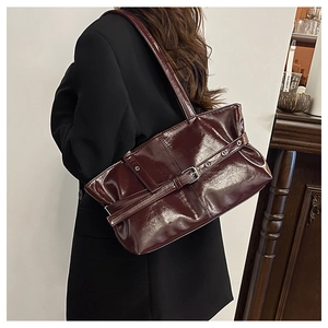 Detail of burgundy patent leather tote bag with metallic buckle and shoulder strap