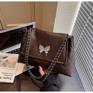Détail du sac matelassé marron avec fermoir papillon argenté et bandoulière en chaîne
