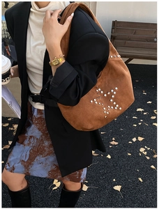 Close-up of silver rivet star pattern on brown suede tote bag with wide shoulder strap