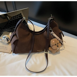 Dettaglio della borsa hobo in pelle scamosciata marrone con logo oro e charm a cucciolo