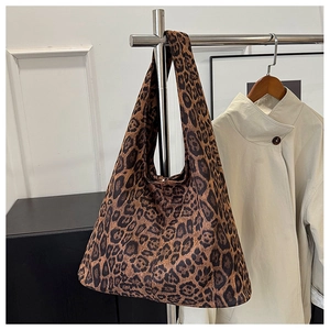 Detailed view of leopard print tote bag hanging on a minimalist silver metal display stand