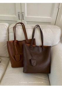 Minimalist leather bucket bags in brown and dark coffee on a beige sofa