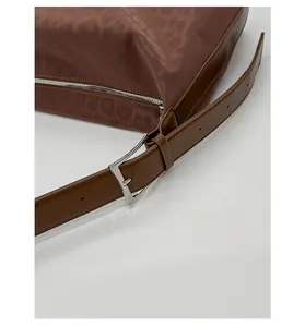 Detail of adjustable leather strap with silver buckle on leopard print crossbody bag