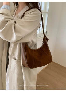 Close-up of a retro brown suede croissant hobo bag with stitched leather detailing