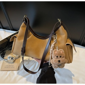 Dettaglio della borsa tote in pelle scamosciata color cammello con ciondolo a orsetto
