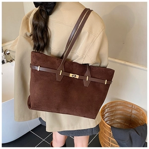 Detail of dark brown suede tote bag featuring a metallic turn-lock and leather straps