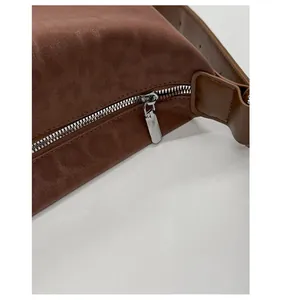 Detailed macro view of the smooth silver metal zipper on the brown suede leopard bag