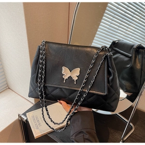 Détail d'un sac bandoulière en cuir matelassé noir avec fermoir papillon argenté et chaîne