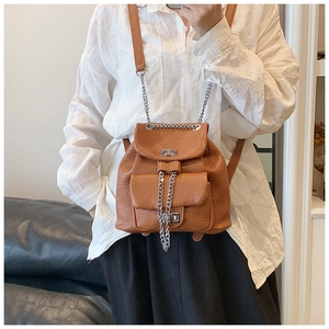 Detail of caramel textured leather backpack with gold chain strap and turn-lock closure