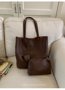 Detailed view of the dark brown bucket bag with lychee texture on a soft sofa
