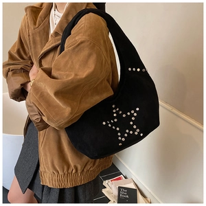 Detail of silver rivets star pattern on black suede hobo shoulder bag with a model