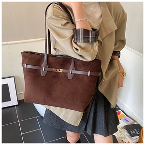 Detail of dark brown suede tote bag featuring a vintage gold metal twist lock and belt strap