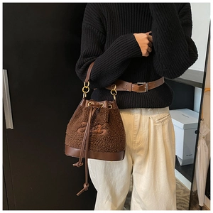 Detail of plush brown shearling bucket bag with drawstring and leather trim