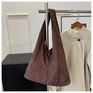 Close-up of brown suede tote bag with minimalist design hanging on a metal rack