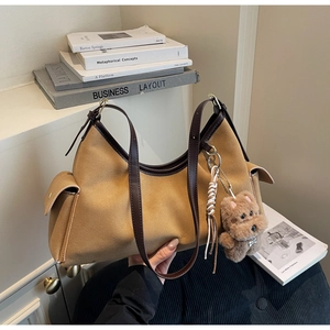 Dettaglio della borsa tote in pelle scamosciata color cammello con ciondolo a forma di orso