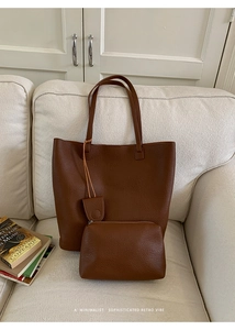 Detail of dark brown lychee leather tote bag and matching inner pouch on a sofa