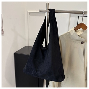 Close-up of minimalist black suede hobo bag hanging on a rack in a modern interior