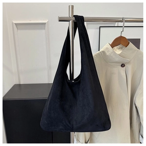 Detail of a black matte suede tote bag hanging on a rack showing its large capacity