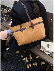 Detailed outdoor shot of a vintage mustard yellow suede tote bag with a golden lock