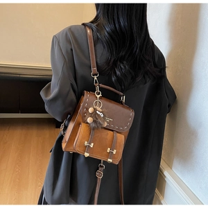Dettaglio di un mini zaino vintage in pelle marrone con ciondolo in peluche su una modella