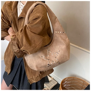 Brown suede underarm bag with silver rivet star pattern shown in a lifestyle setting