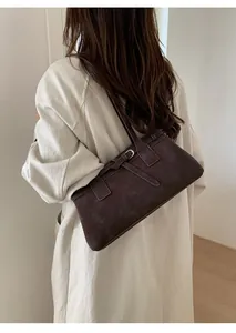Detail der dunkelbraunen Wildleder-Schultertasche mit Silberschnallen am Model