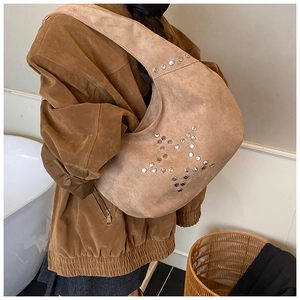 Detail of studded star pattern on vintage suede tote bag worn by model over shoulder