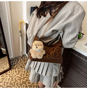 Detailed view of leopard print crossbody bag with a cute plush bear charm on a model