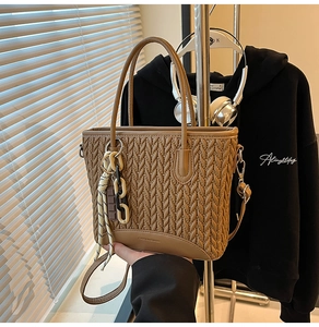 Close-up of brown quilted bucket bag with V-shaped woven texture and adjustable strap