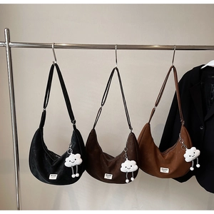 Close-up of three suede hobo bags with cloud pendants hanging on a studio rack