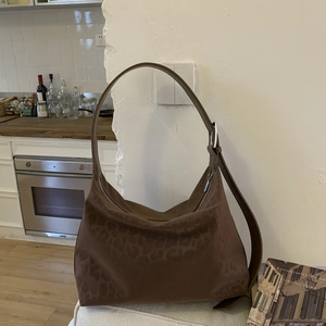 Macro detail of brown leopard print hobo bag showing texture and silver hardware buckle